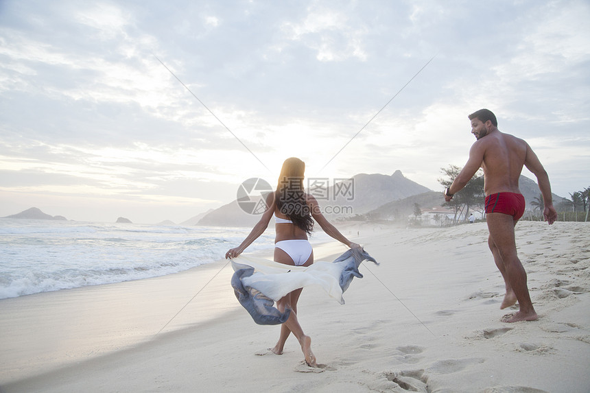 站在海边沙滩散步的情侣背影图片