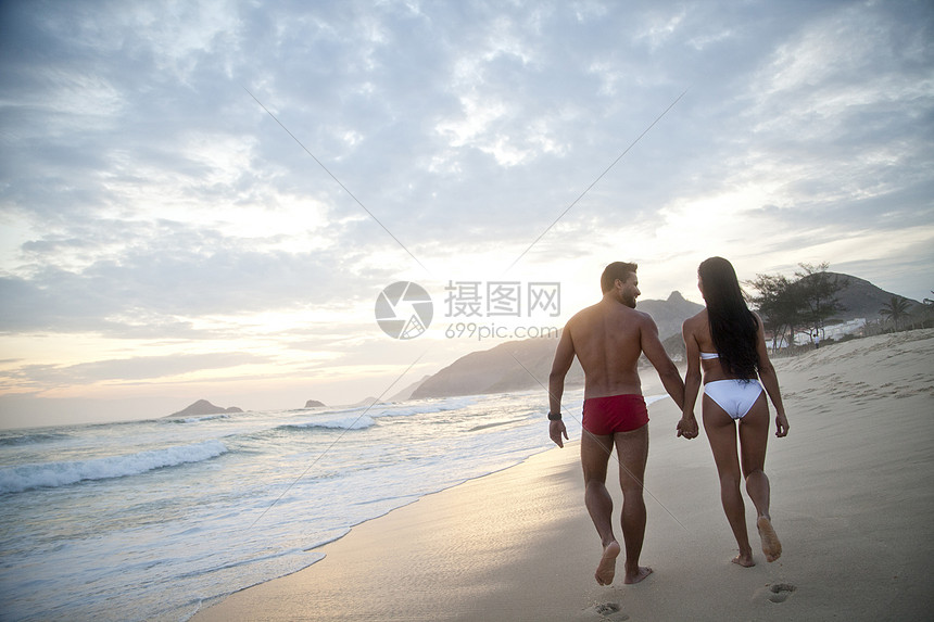 站在海边沙滩散步的情侣背影图片