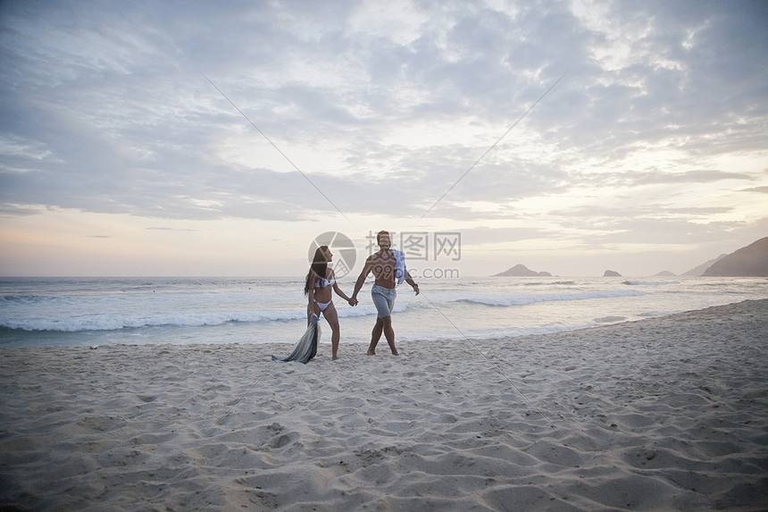 站在海边沙滩散步的情侣图片