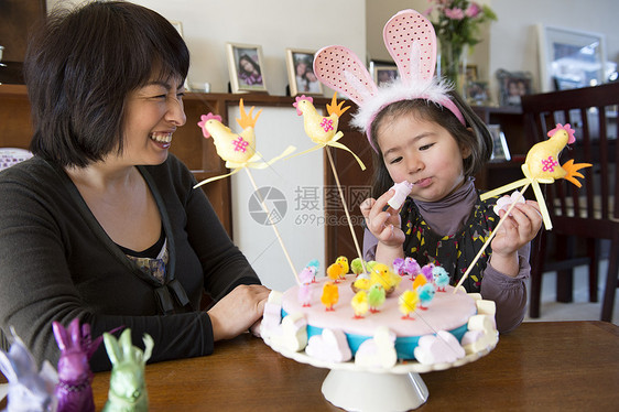 母亲和女儿看着摆在桌上的复活节蛋糕图片