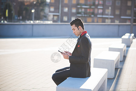 青年商人坐在石凳上使用平板电脑图片