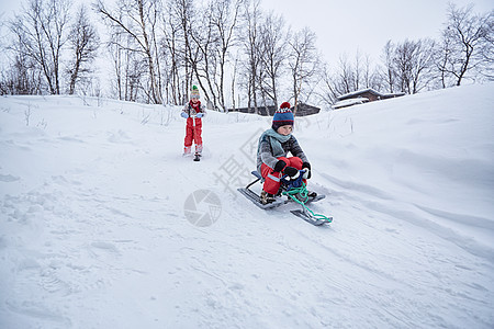 两位小朋友在雪中骑车图片