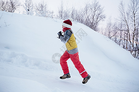 男孩在雪覆盖的山丘上奔跑图片