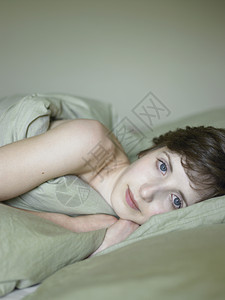 美丽的年轻女人躺在床上肖像图片