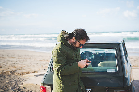 海滩上开汽车的男人在使用手机图片