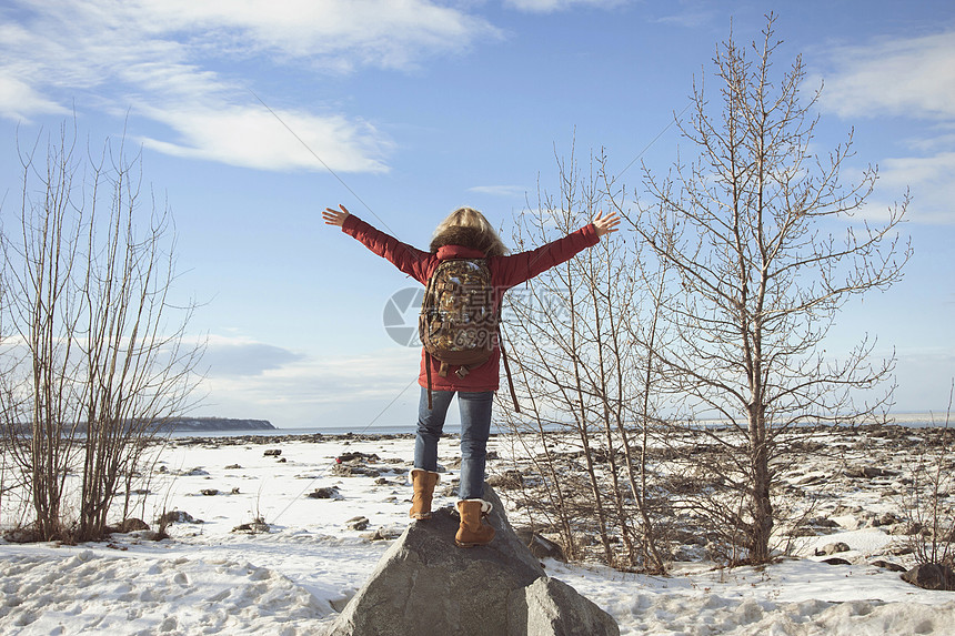 妇女伸出双臂站在岩石上图片