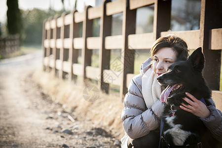 年轻女子和狗狗在乡村车道上的肖像图片