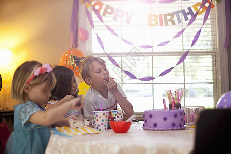 三个孩子坐在桌边吃生日蛋糕图片