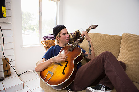 坐在沙发上弹吉他的年轻人图片