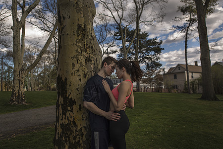 浪漫的年轻运动夫妇在黄昏公园拥抱图片