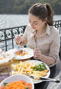 年轻妇女在湖边餐馆吃西餐背景图片