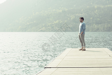 湖边码头上欣赏风景的男子背景图片