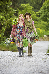 两名妇女沿农村公路携带蔬菜行走的肖像图片