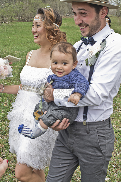 新娘和郎抱着男婴在田间走过图片