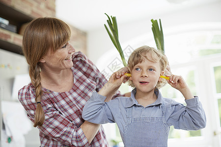 母亲和儿子在厨房里玩蔬菜图片