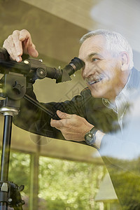 家里的资深男子用望远镜穿过窗户图片