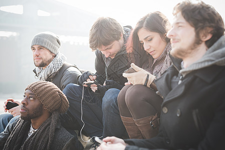5个青年朋友坐在一起用智能手机联网图片