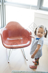在客厅的红摇椅旁边站着的可爱女孩图片