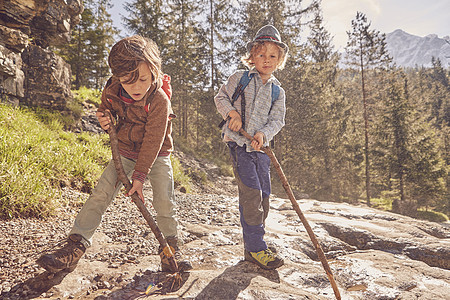 两个年轻男孩拿着棍棒探索森林图片