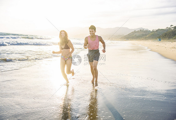 在海滩上奔跑的年轻夫妇图片