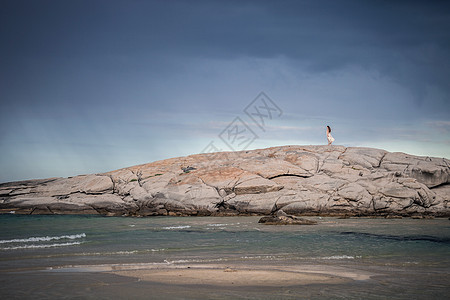 在意大利撒丁岛科斯塔赖伊海岸的岩石形成上漫步的年轻女子远视图片