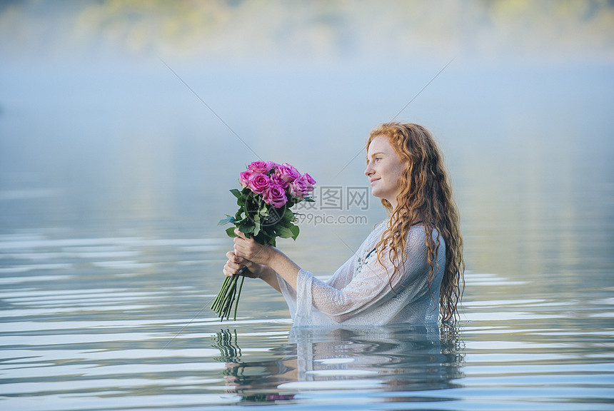 年轻女人站在湖边看着一堆粉红玫瑰图片