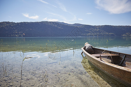 男孩从划船往前弯腰看着湖图片