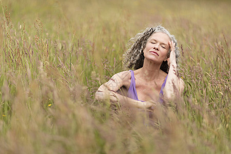 成熟的女人坐在草地上闭着眼睛图片
