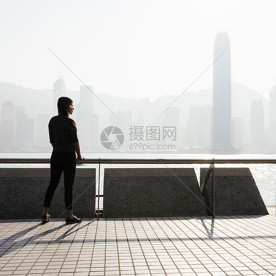 站在香港天线前望水边的年轻女子图片