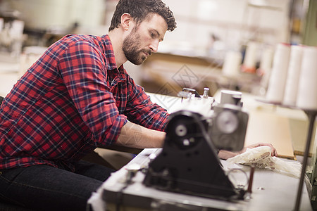 在旧纺织厂使用缝纫机的成年男子图片