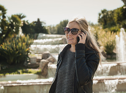 站在喷泉前的女游客使用智能手机聊天图片