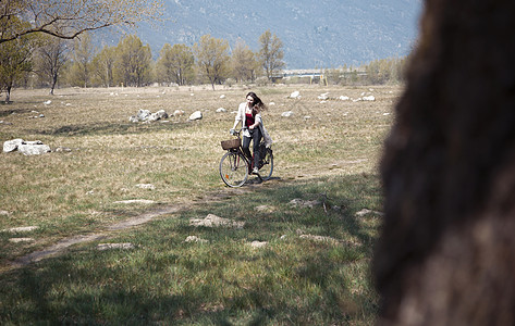 沿农村轨道骑自行车的年轻妇女图片