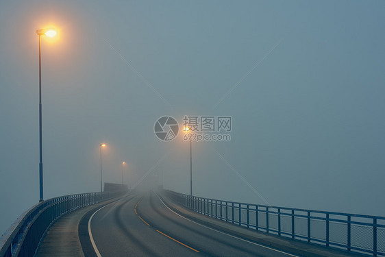 挪威罗加兰县豪格松街道灯光照明下迷雾道路的渐弱透视图图片