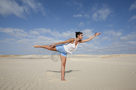 妇女在沙滩上伸展练习瑜伽图片