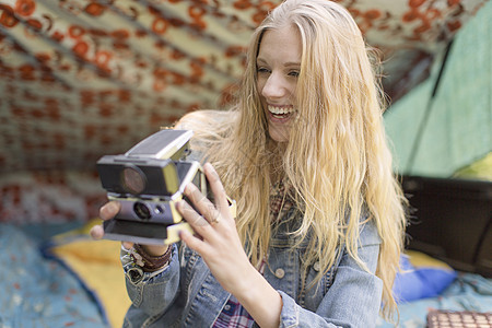 年轻妇女在露营时用拍立得拍照图片