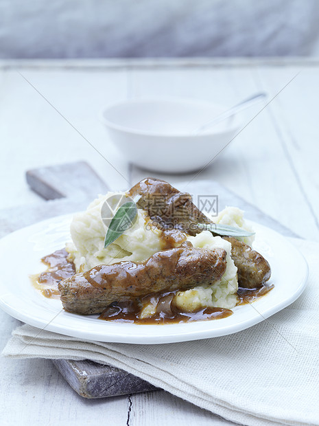 白盘上的香肠土豆泥和肉汁图片