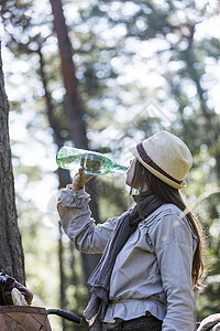 从森林中用水瓶喝水的骑自行车的妇女图片