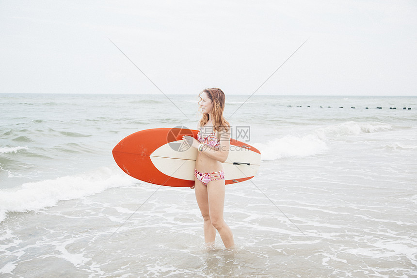 成年中女在海上站立手持冲浪板图片