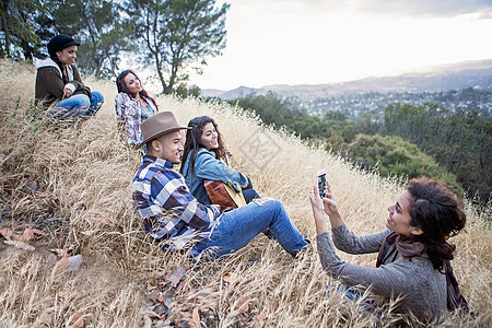 年轻女子在草地山上给朋友拍照图片