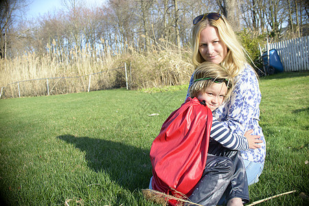 母亲拥抱着穿着超级英雄斗篷的儿子图片