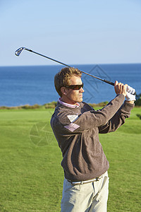 高尔夫球手戴着太阳眼镜挥球图片
