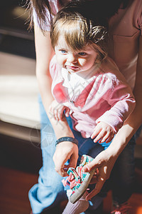 成年妇女给幼儿穿上幼儿教练鞋图片