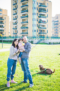 中成年夫妇的肖像与幼儿女和狗在公园图片