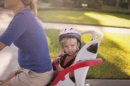 骑自行车的成人儿坐在孩子的座位上坐在她身后图片