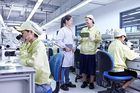 在生产电子路板的工厂质量检查站的年轻女性图片