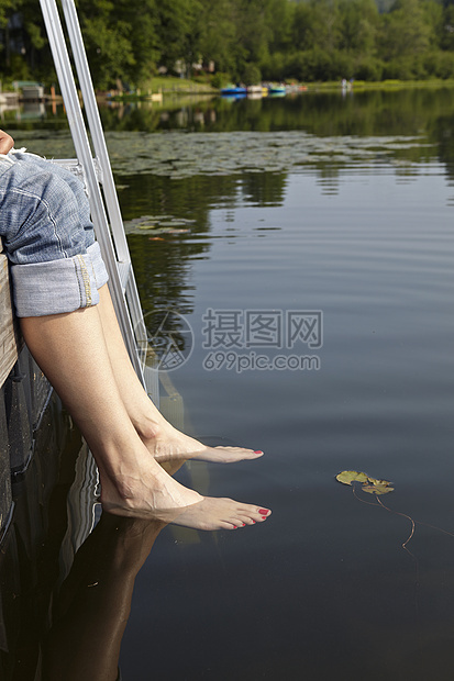 湖边码头赤脚放入水中的女人图片