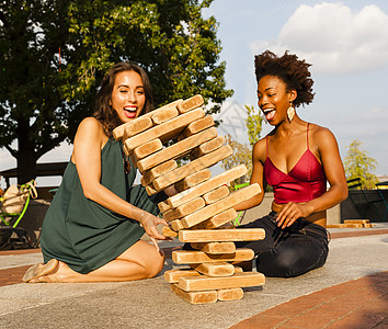 青年妇女在地板上玩抽积木游戏图片