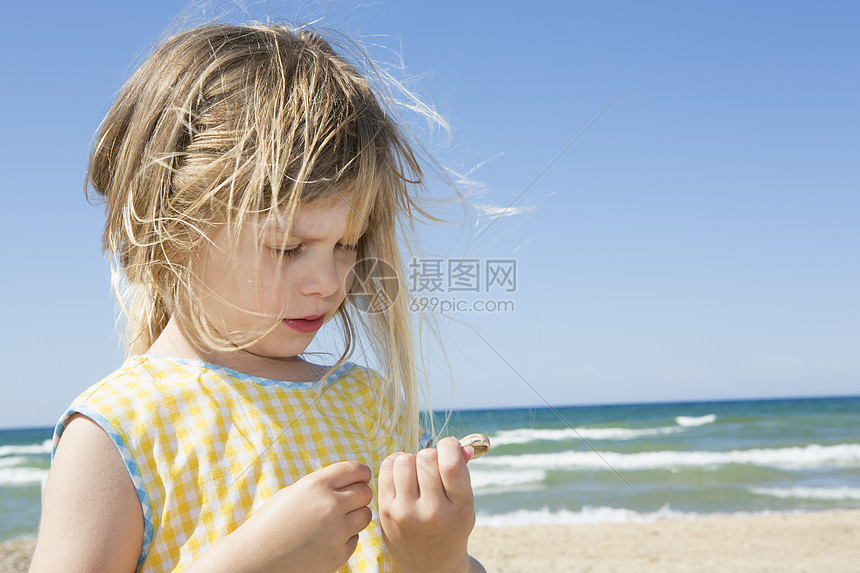 在海滩边捡贝壳的小女孩图片