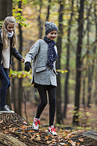 秋季森林中在树干上行走的女孩图片