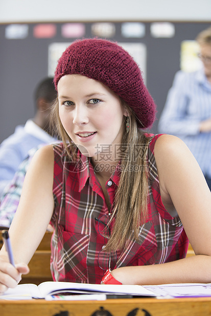 坐在教室的办公桌前的女学生肖像图片